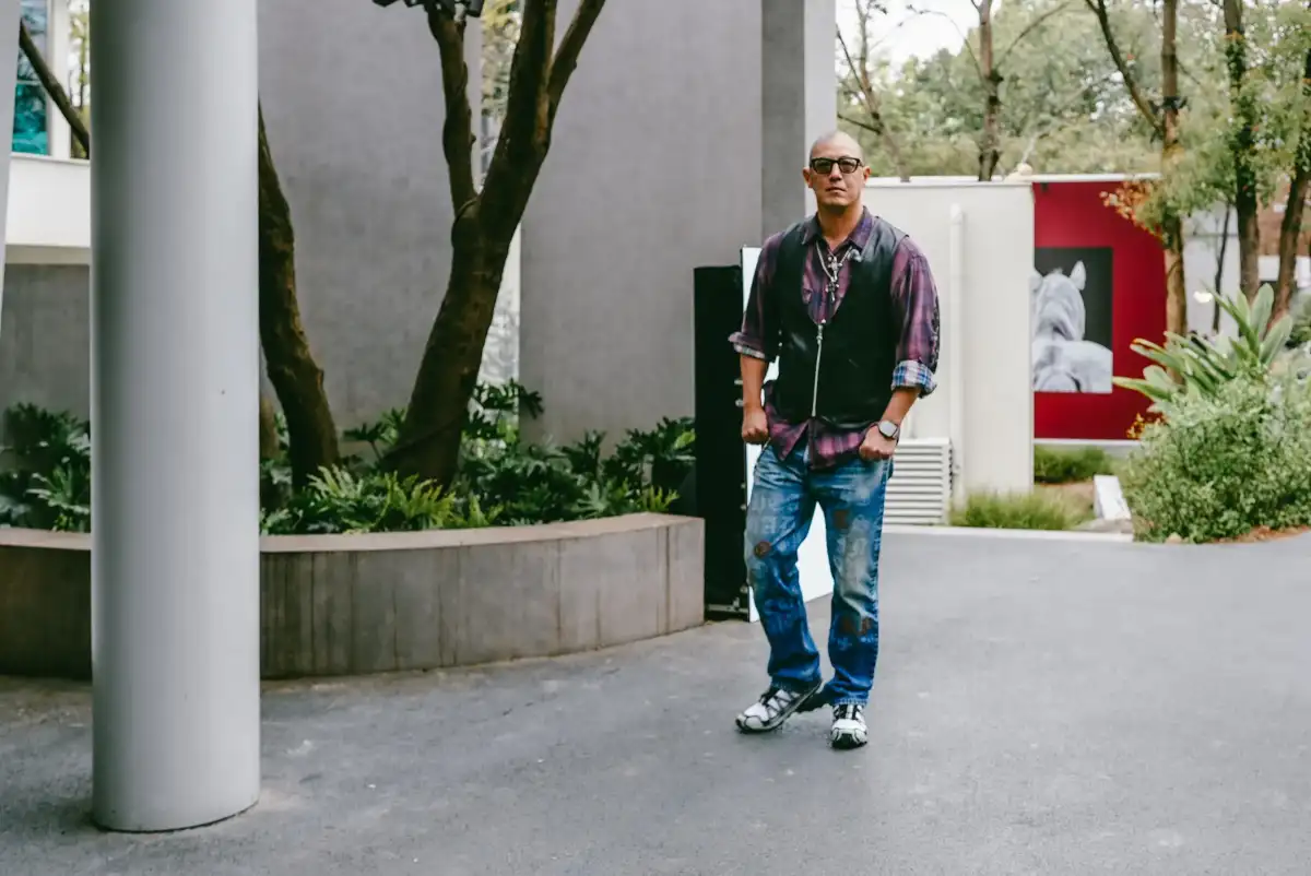 A standing portrait of a man inside a quiet courtyard.