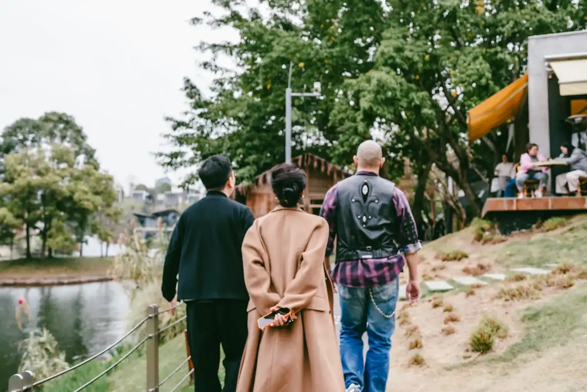 Three people walking away beside a lake toward a programme site.