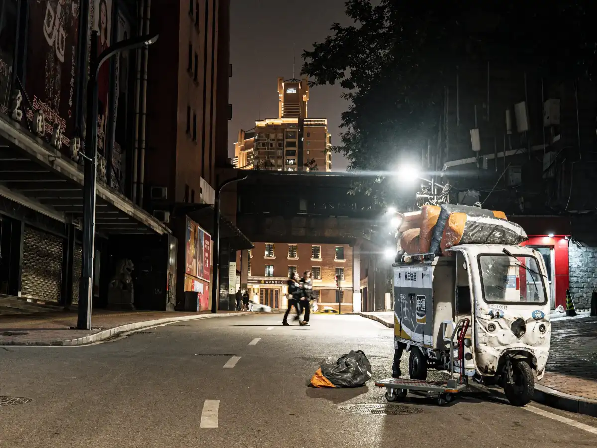 A small street vehicle parked on an empty road at night.