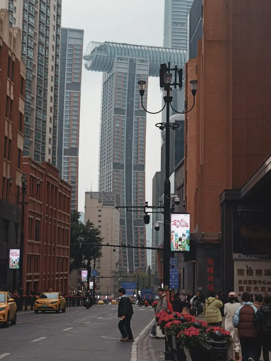 A dense urban street compressed between towers and brick facades.