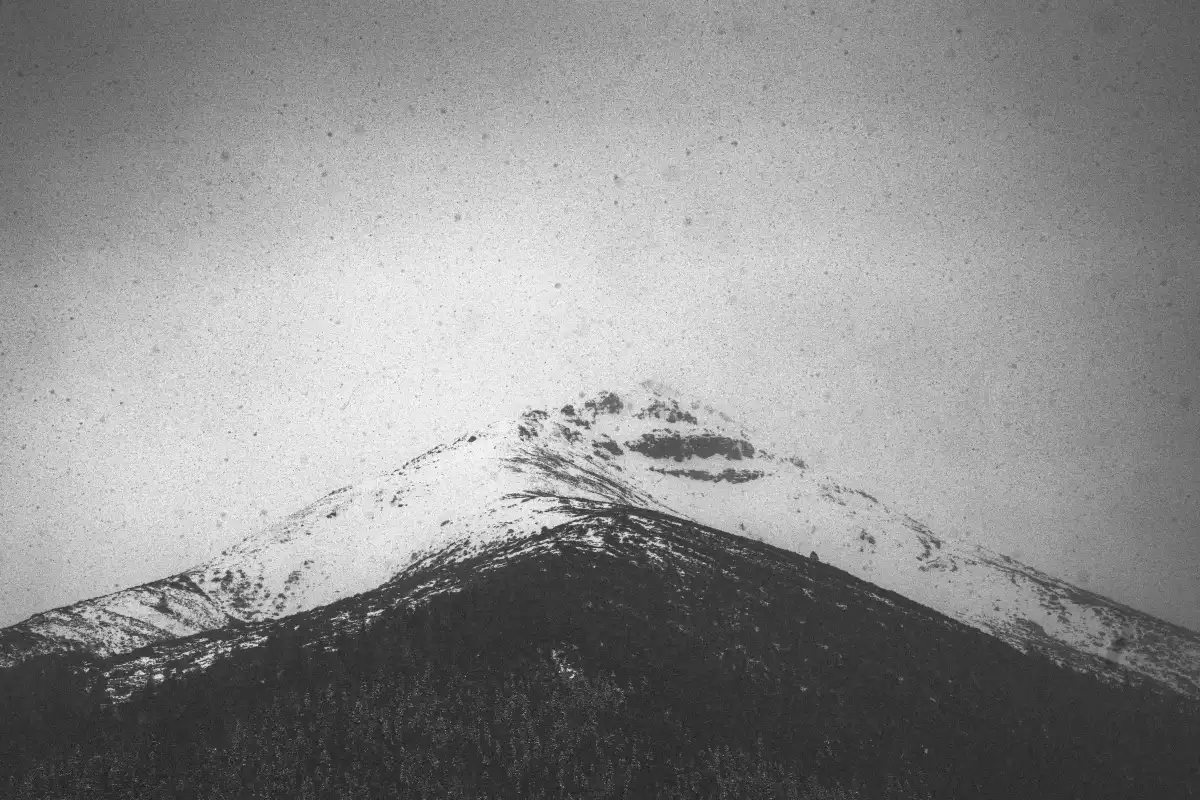 A monochrome snow ridge held above a dark mountain mass.