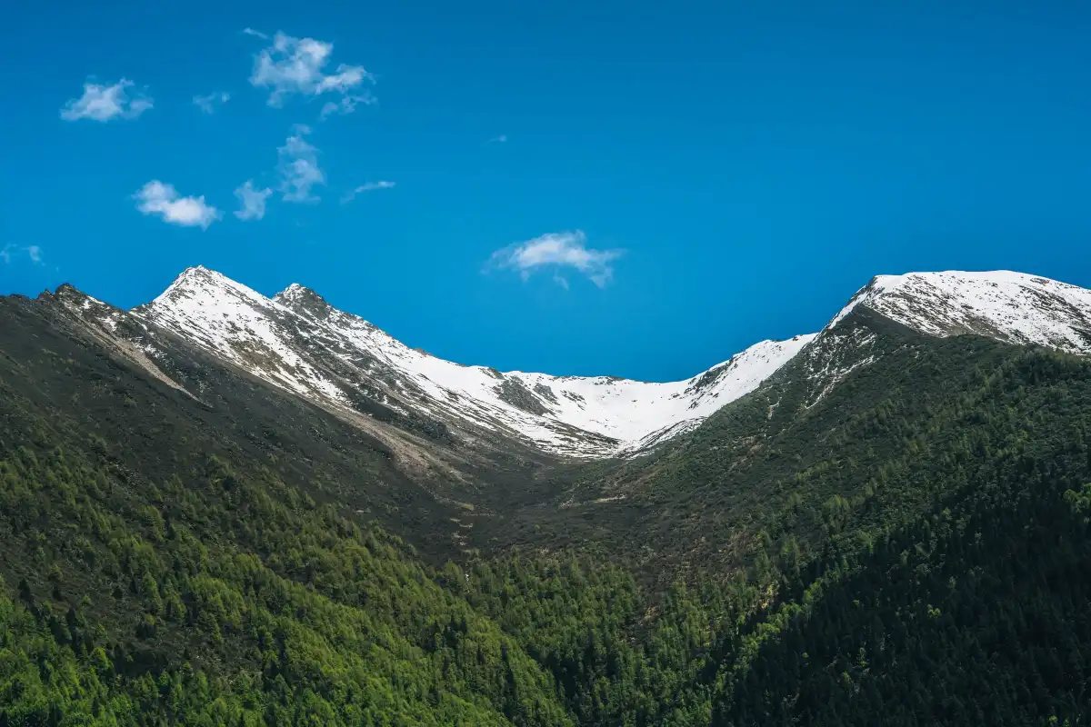 A broad snow basin opening above dark green slopes in Siguniang Mountain.